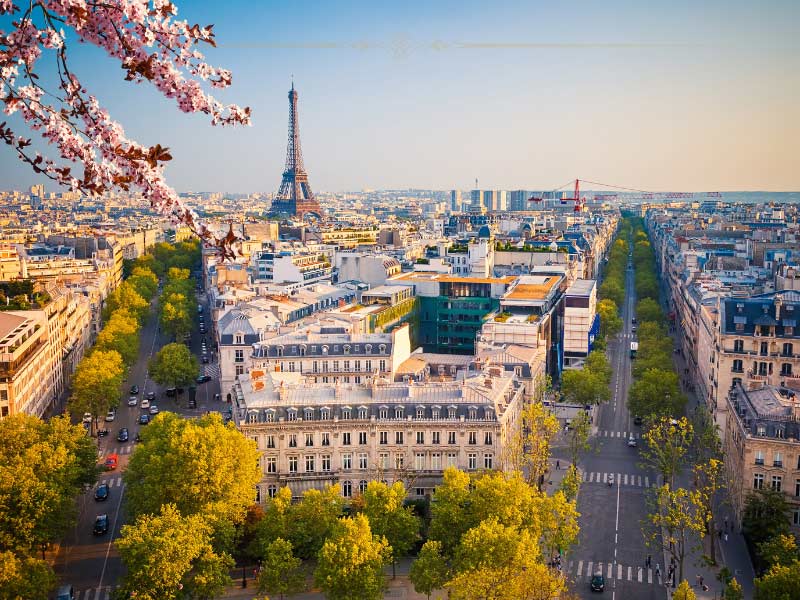 A photo of Paris in spring, showing an aerial view of Paris, with the Eiffel Tower in the background and the Champs Elise boulevard on the right.