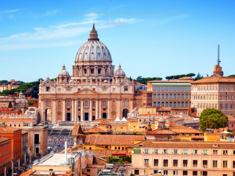 A photo of St Peter's Basilica and the Vatican taken from the terrace of Castel St Angelo on a sunny day.