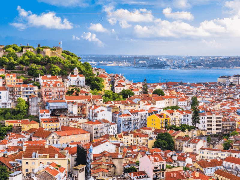 An aerial view over Lisbon, with the town lower than the castle. You can see the sea in the back.