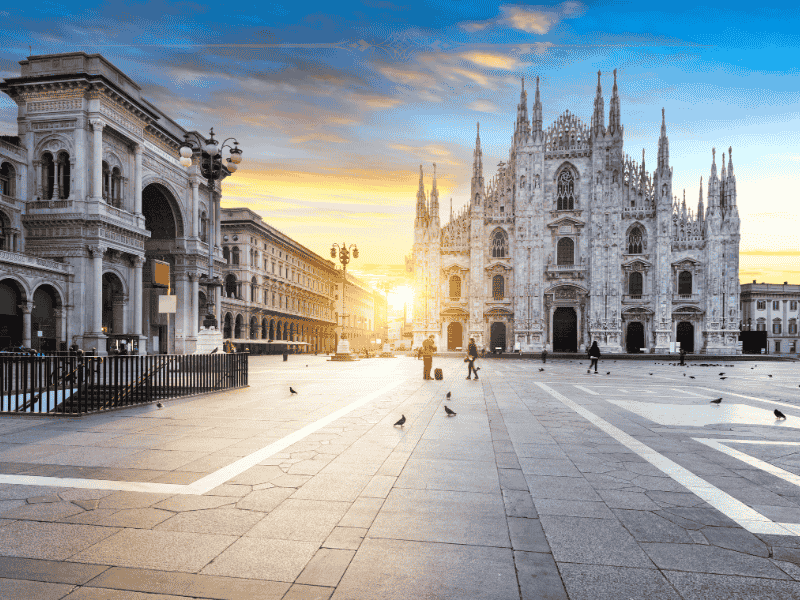 A photo of the Duomo in Milan at sunrise. The sun is rising from the left hand side of the duomo.