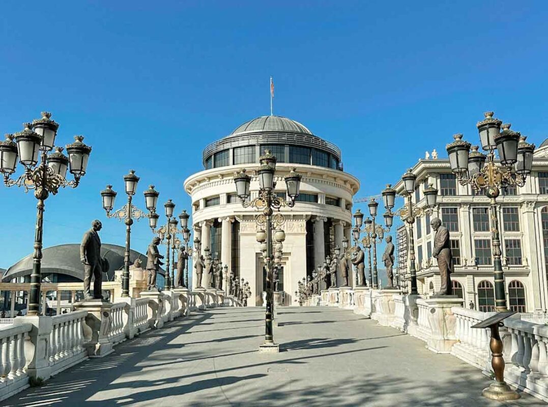 A bridge leading to a round building with a cupola on the top, on a clear, sunny day.